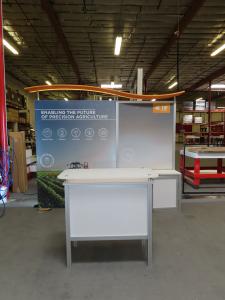 ecoSmart Sustainable ECO-1102 Exhibit with Backlit Fabric Graphic, Wave Canopy, Locking Backwall Cabinet, Monitor Mount, LED Lights, and MOD-1552 Reception Counter with Storage